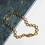The gold-plated MLE Gentlewoman's Agreement Necklace on green marble surface